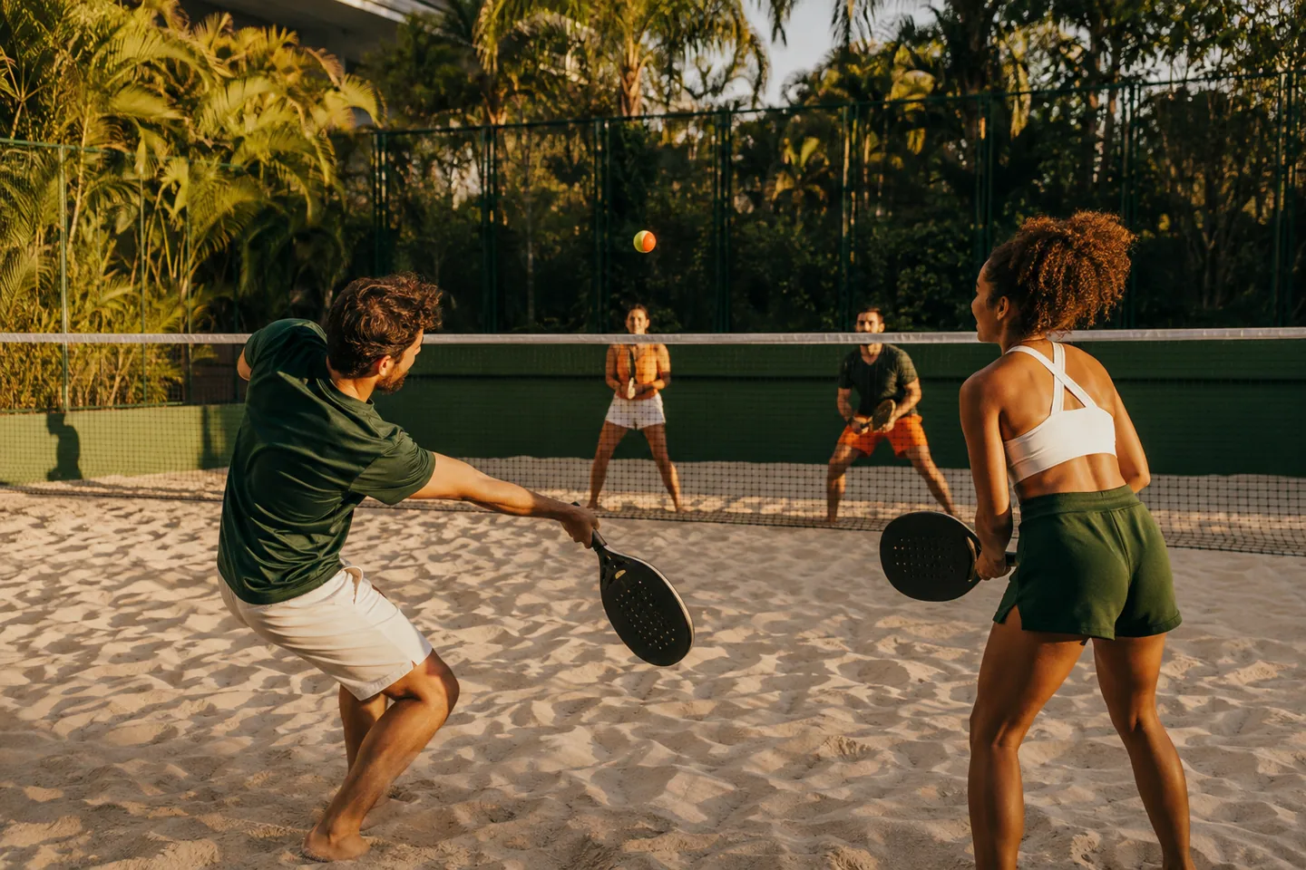 Amigos em uma partida de beach tennis ao pôr do sol